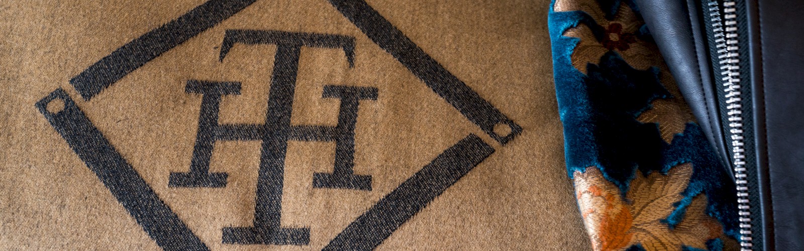 This image shows a geometric logo on fabric next to a leather jacket with floral lining.