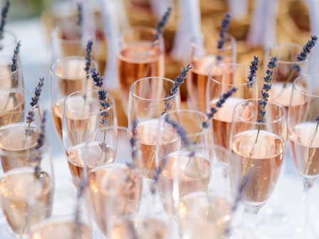 Glasses of champagne with lavender sprigs are arranged on a table, creating a beautiful and festive display.